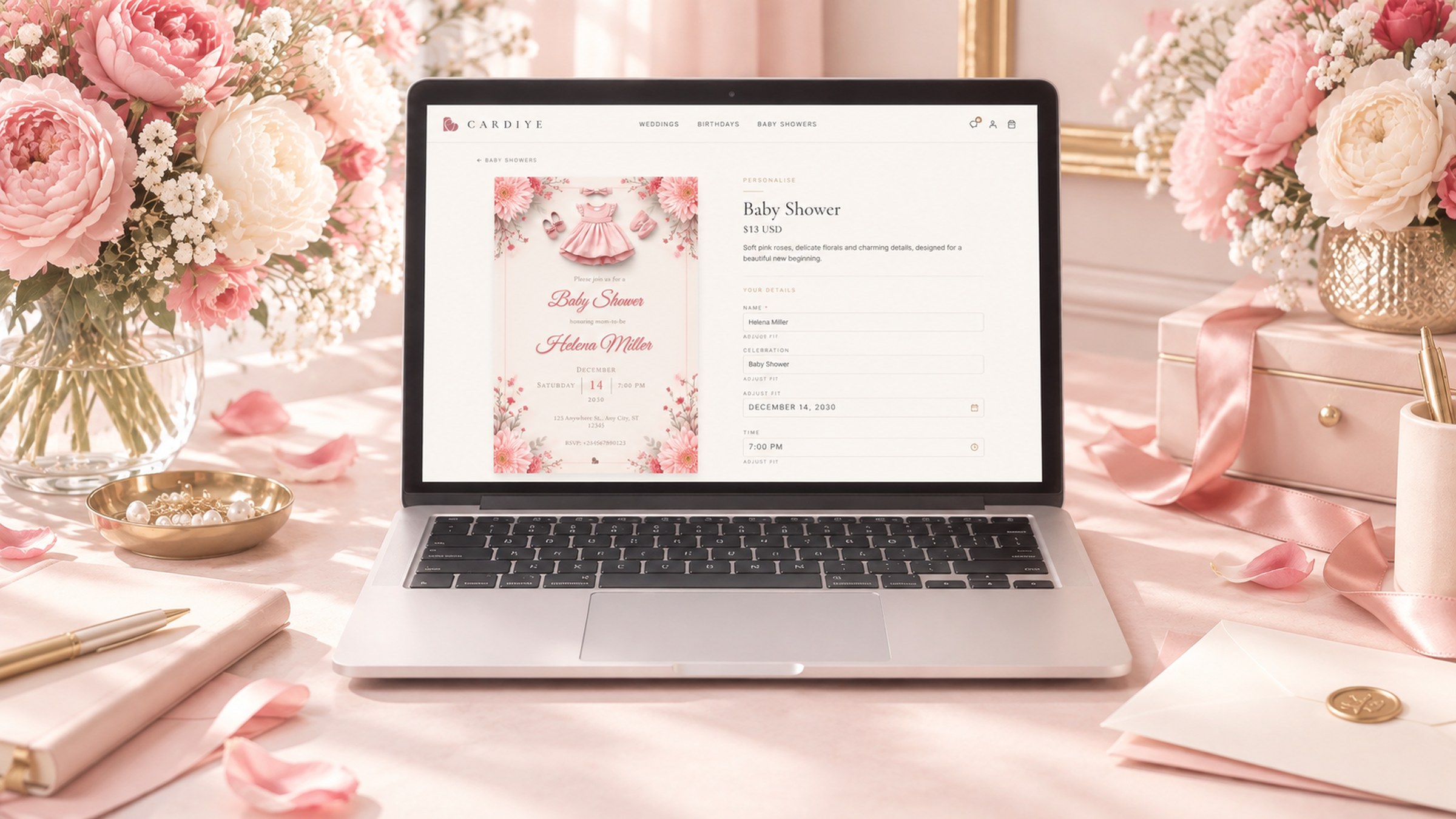 A laptop showing the CARDIYE personalization page for a pink floral baby shower invitation, surrounded by peonies and pink ribbon